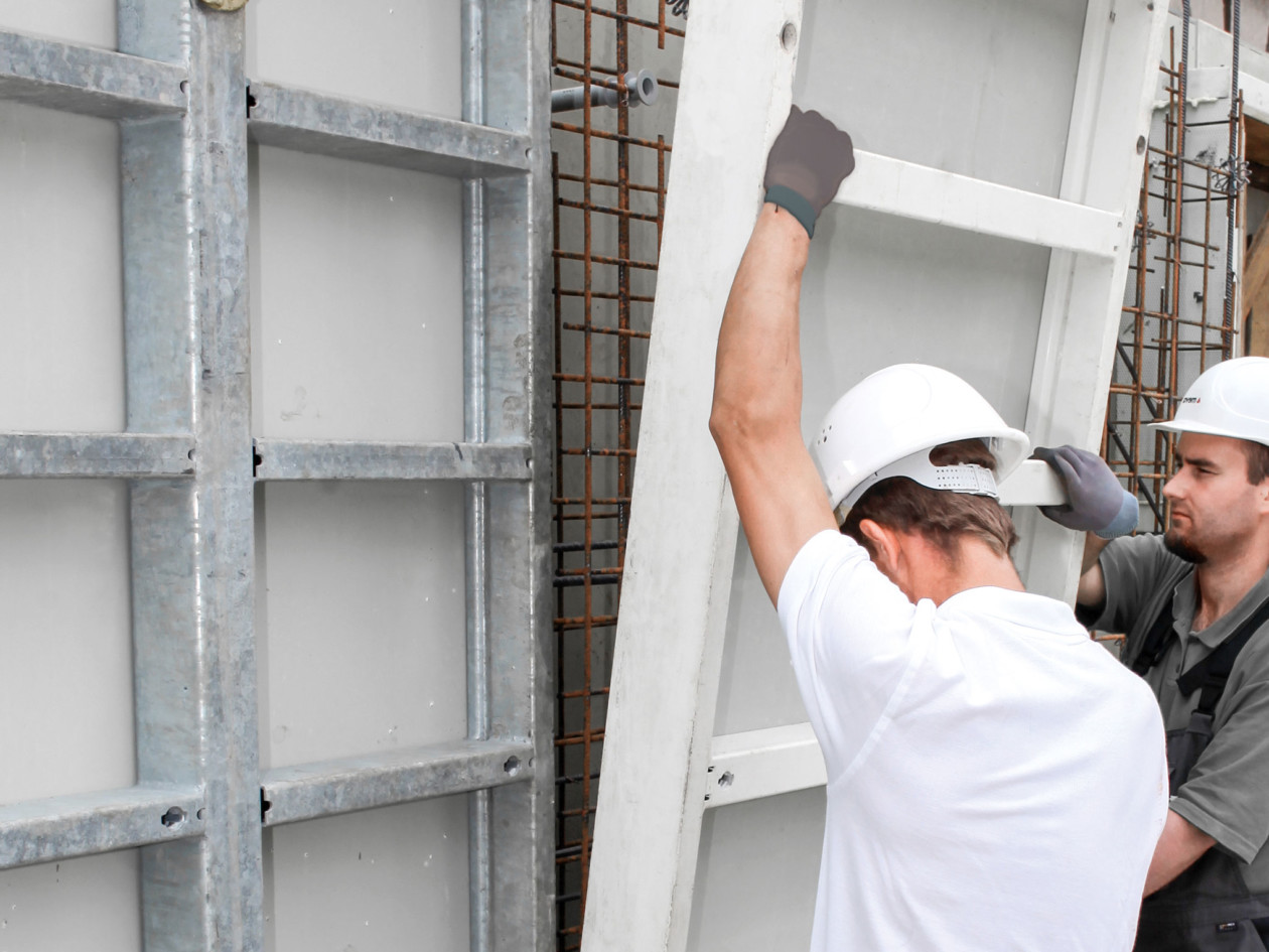 Two men fitting together lightweight formwork panels